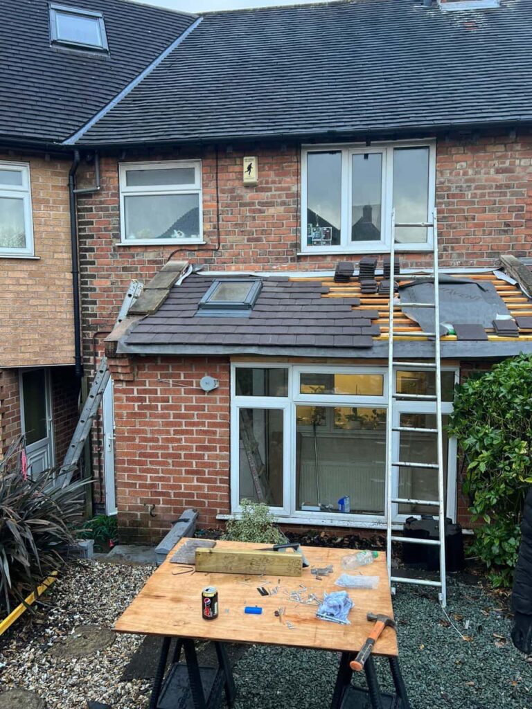 This is a photo of a roof extension that is having new roof tiles installed. This is a photo taken from the roof ridge looking down a tiled pitched roof on to a flat roof. Works carried out by Bedworth Roofing Repairs